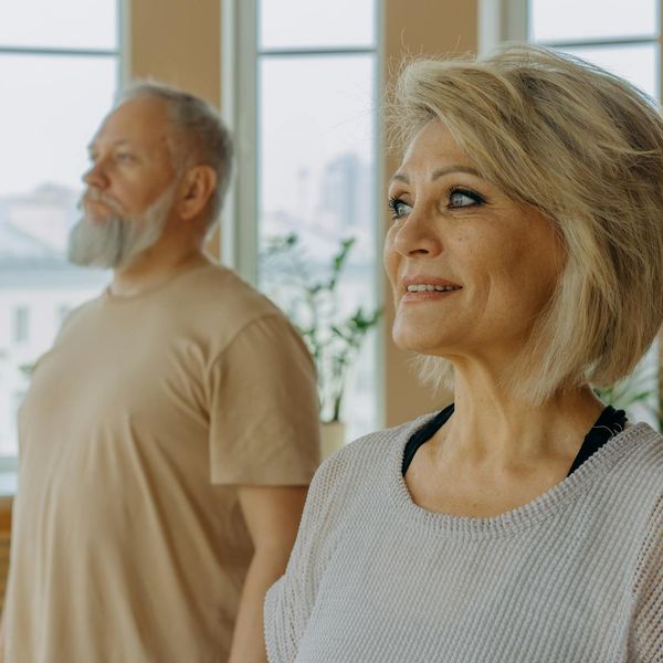 Group of people of different ages smiling during a yoga class.